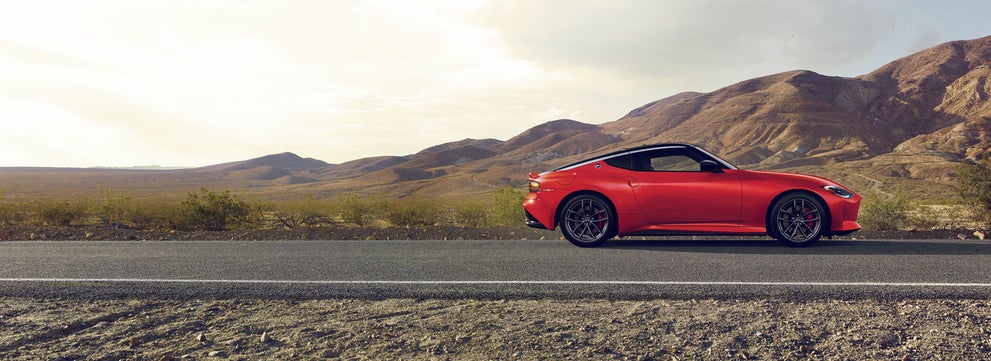 2026 Nissan Z in red driving on a desert road with mountains in the distance