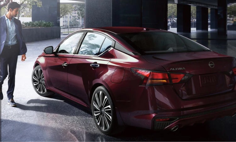 Man walking to the driver seat of a Red Nissan Sedan